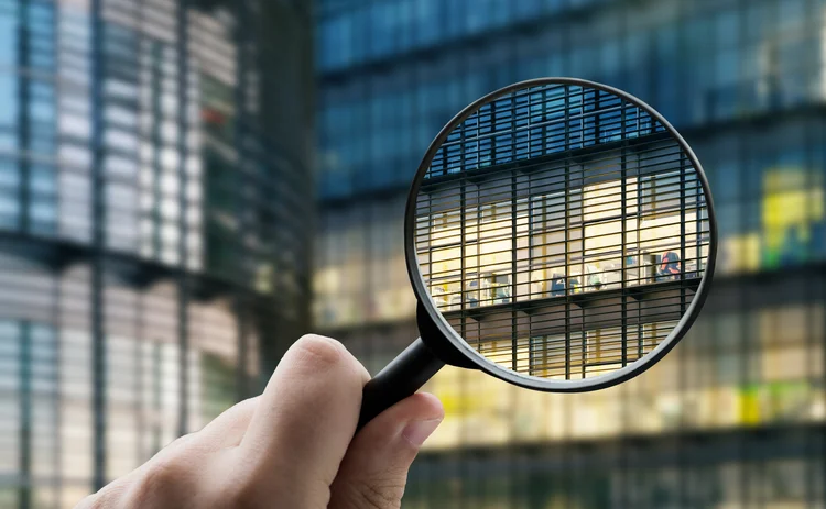 magnifying glass held up to inspect an office building 